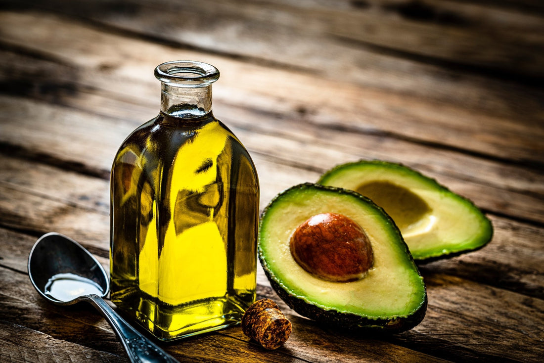 A halved avocado next to a bottle of avocado oil.