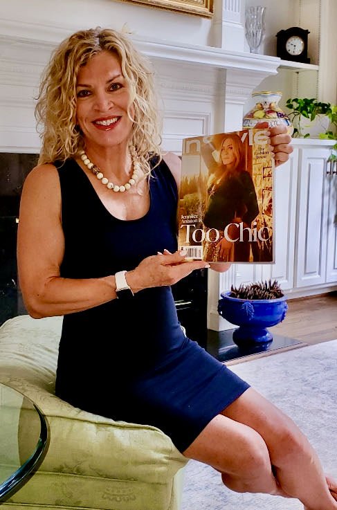 A smiling woman holding a copy of Too Chic magazine featuring Vitali.