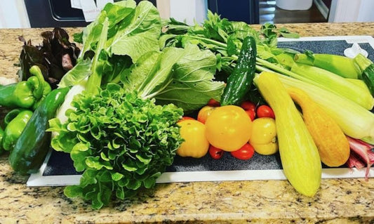 A countertop full of vegetables, including tomatoes, squash, and peppers.