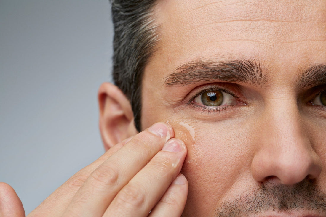 A man performing his skincare routine by applying an under-eye serum.