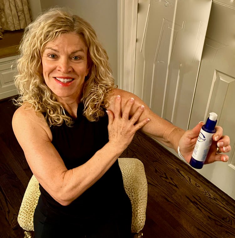 A woman holding out a bottle of Restoracell (Vitali) skin cell awakening serum.