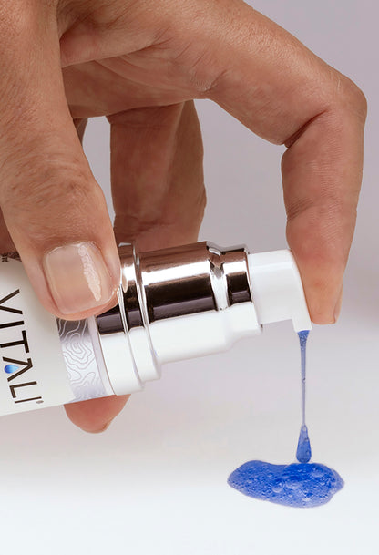 Vitali's blue copper peptide skincare product being pumped from the bottle.