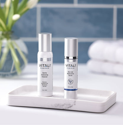 Two small skincare bottles, one a gentle exfoliating cleanser and one a skin cell restorative serum.